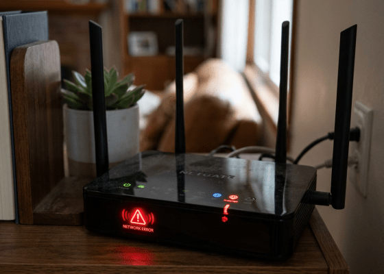 WiFi router showing red network error light on wooden shelf
