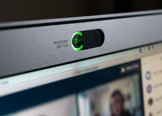 Laptop webcam with green active light and privacy cover above video call screen
